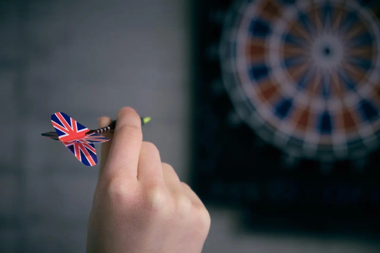 Hånd der holder en dart foran en dartskive
