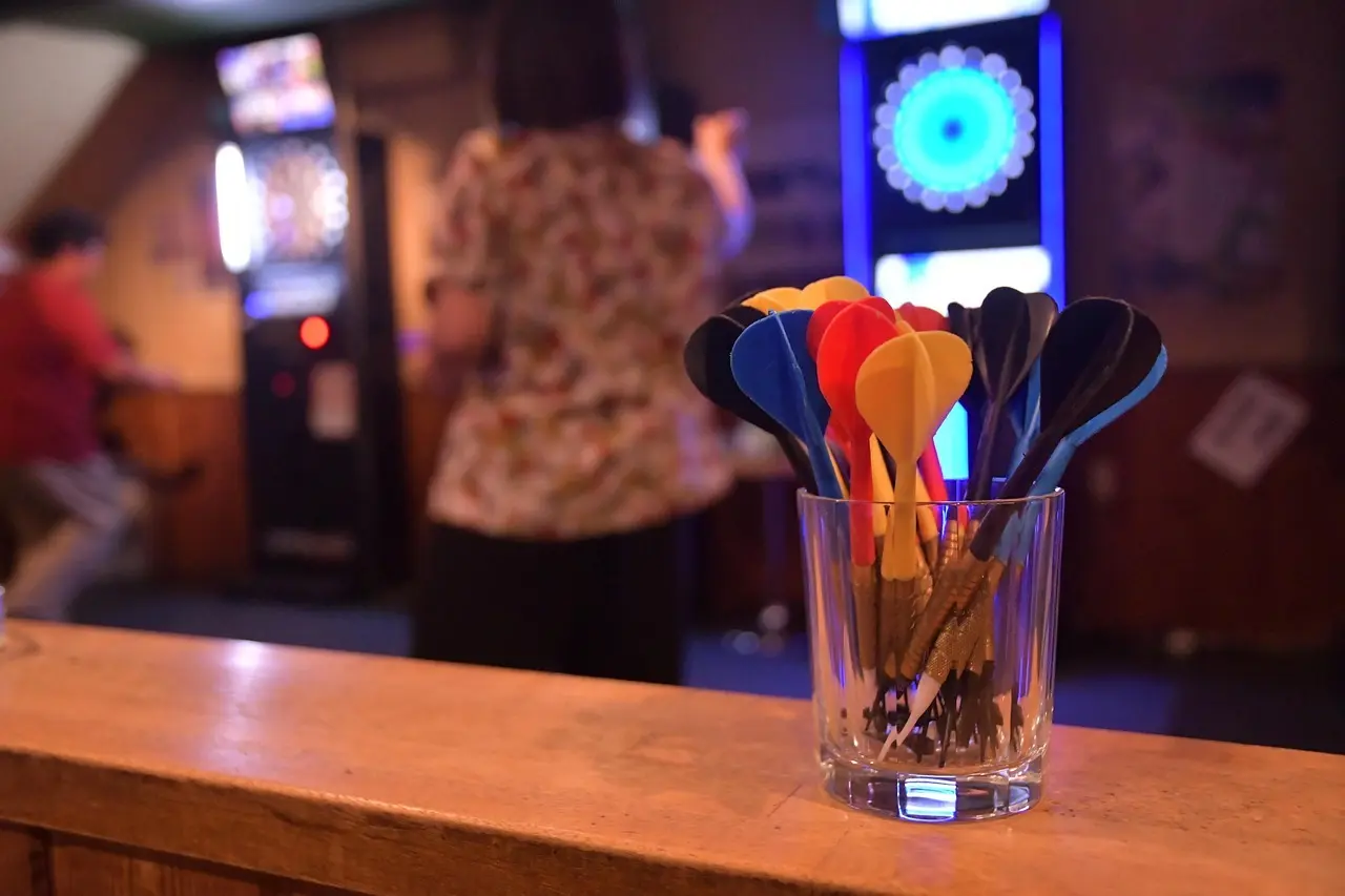 Glas med dartpile foran elektronisk dartboard